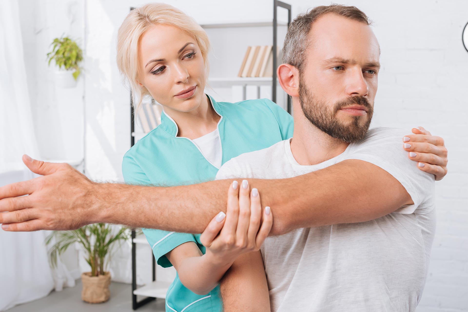 Physiotherapist stretching man's arms